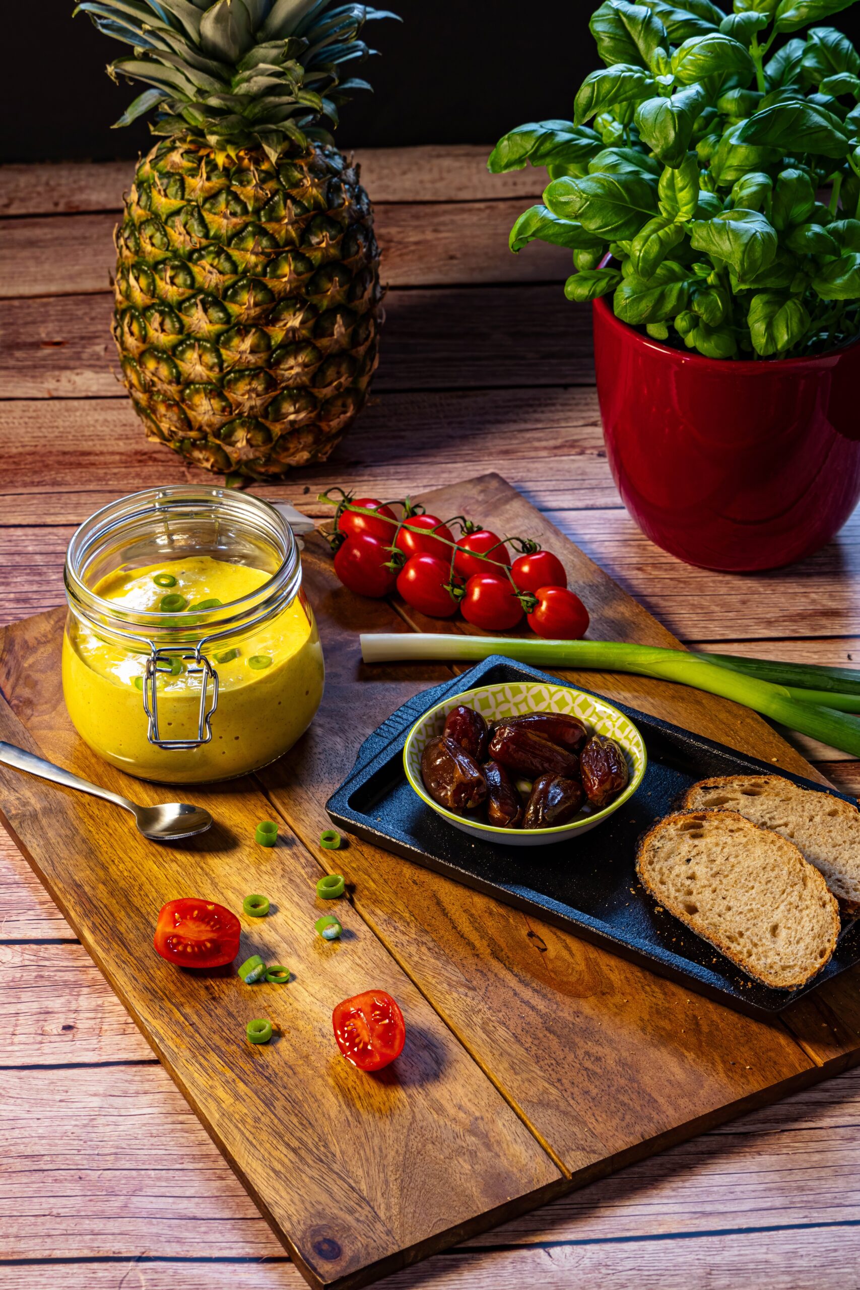 Curry Ananas Dip in einem Glas neben Baguette und Datteln