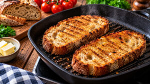 Zwei dicke Scheiben Bauernbrot werden in einer gusseisernen Grillpfanne goldbraun und knusprig geröstet
