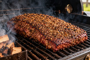 Rinderbrust mit kräftiger Pastrami-Gewürzkruste beim langsamen Räuchern auf dem Rost eines BBQ-Smokers