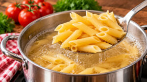 Penne Rigate werden in einem Edelstahltopf mit kochendem Salzwasser al dente gekocht und mit einer Schaumkelle herausgehoben